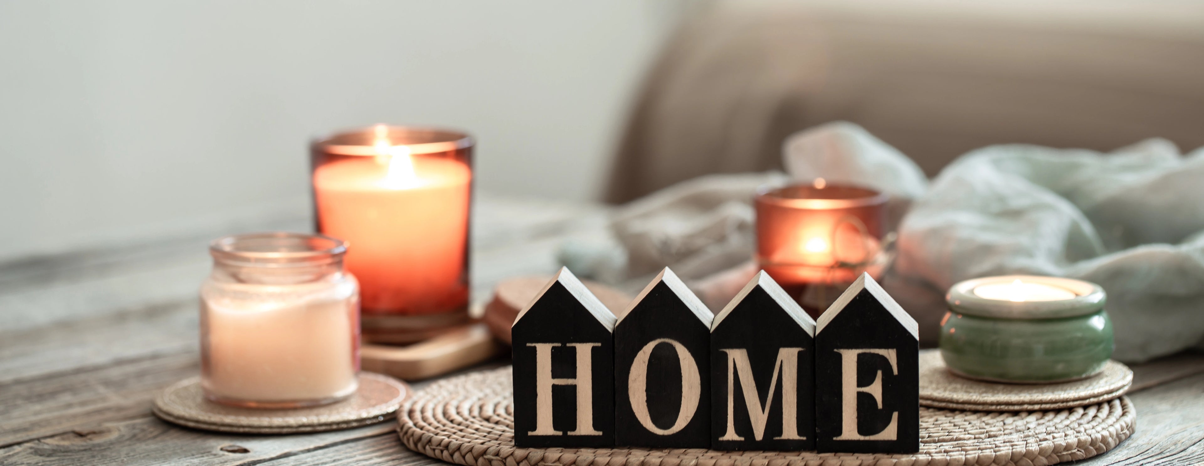 Decorative candles and a wooden block with 'HOME' on a wooden surface.