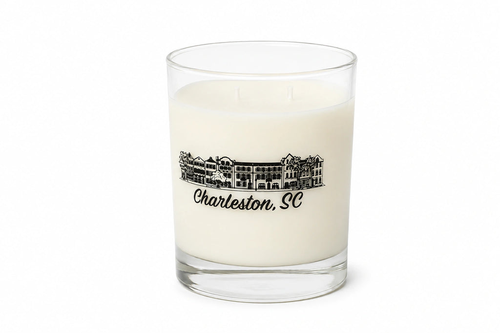 A white soy wax candle in a clear glass jar with a black printed illustration of a historic building and the text 'Charleston, SC' on the front, set against a plain white background.