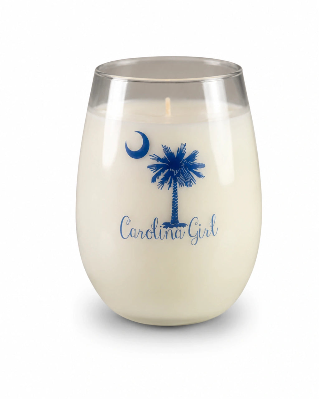 A Santa Barbara 'Carolina Girl' scented candle in a clear stemless glass jar, featuring a blue printed palm tree, crescent moon, and 'Carolina Girl' script on the front.