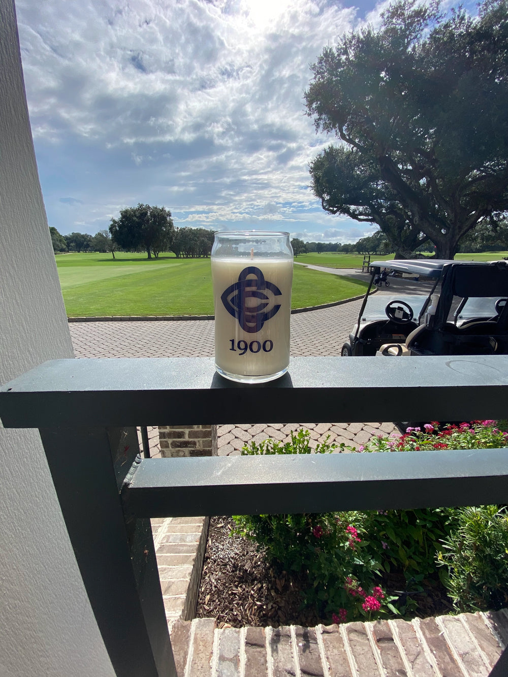 Glass jar with logo and text on a ledge overlooking a golf course