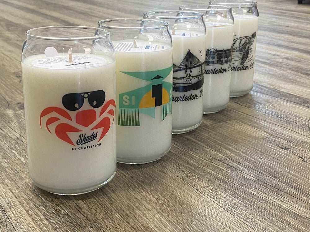 Row of candles in glass jars with various designs on a wooden surface