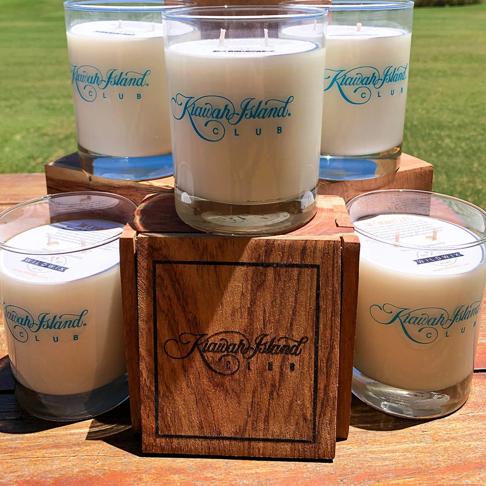 Candles with 'Kauai Island Club' branding on a wooden block outdoors.