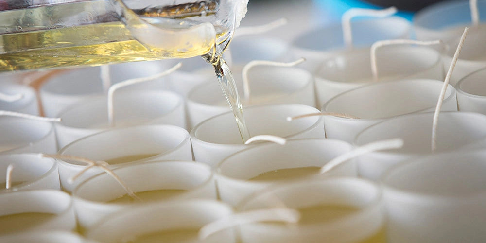 Close-up of white ceramic spoons with oil being poured over them.