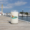 Candle with a fish design on a wooden dock by a marina