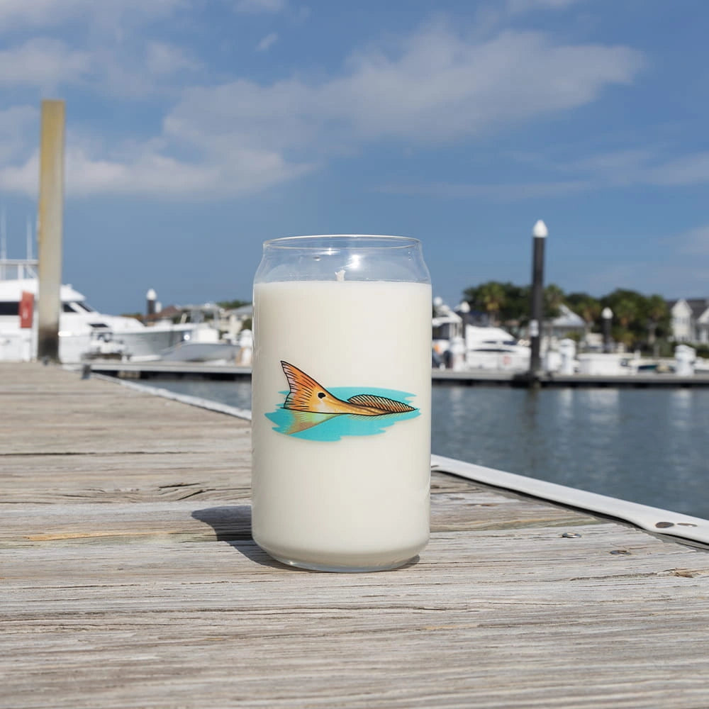 Candle with a fish design on a wooden dock by a marina