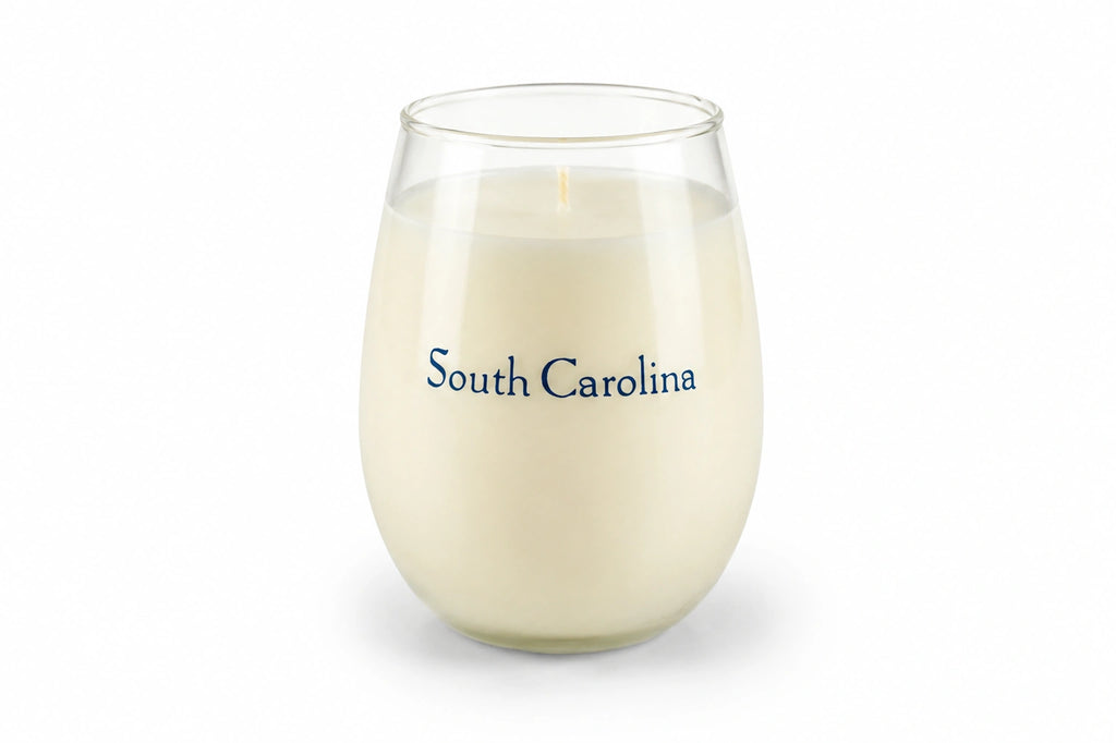 A stemless wine glass candle filled with creamy off-white wax, featuring the words 'South Carolina' printed in blue text on the front, set against a plain white background.