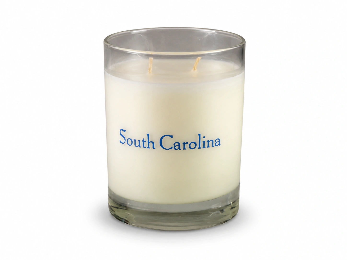 A single-wick scented candle in a clear glass jar with cream-colored wax and the words 'South Carolina' printed in blue on the front, set against a plain white background.