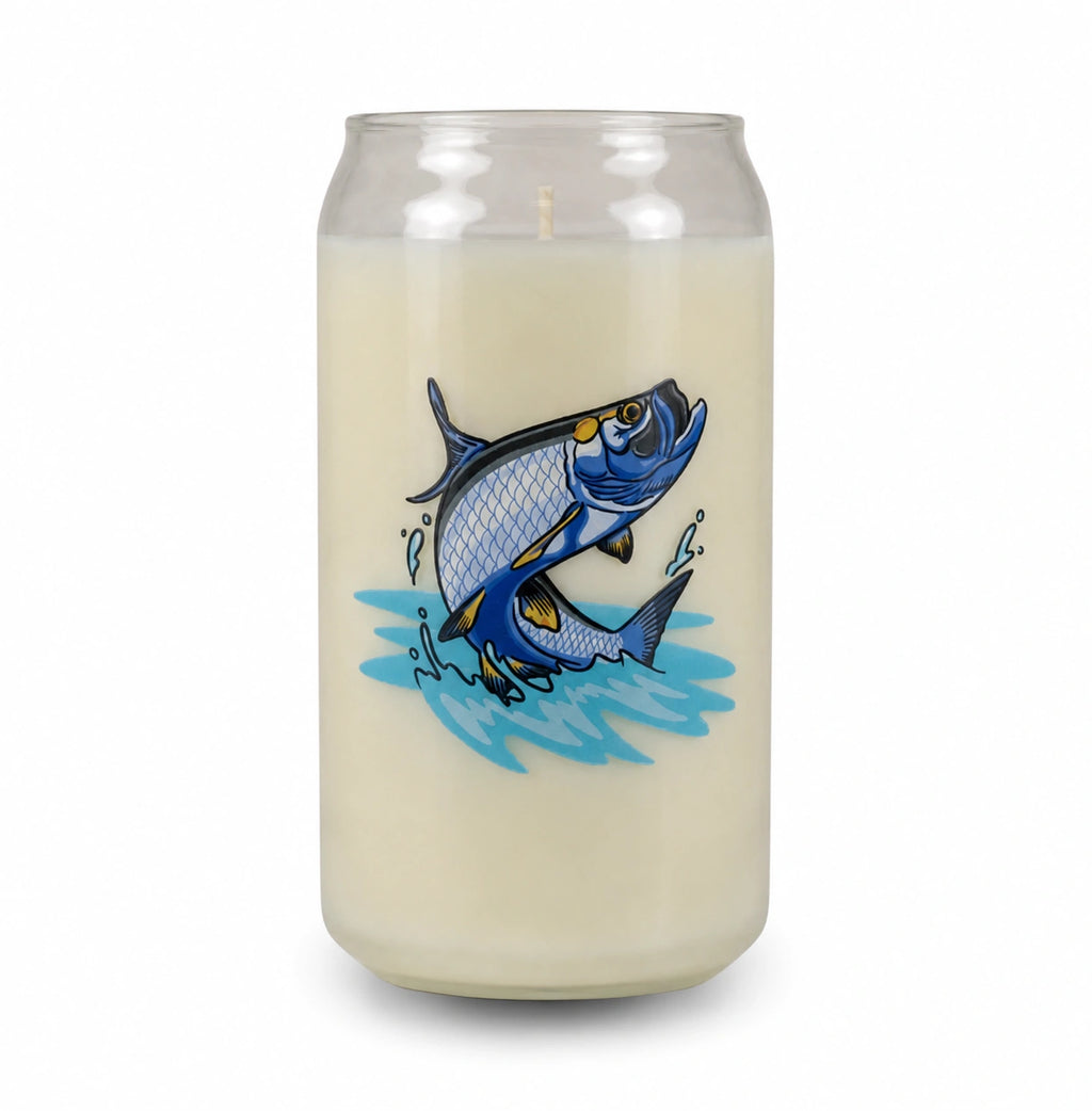 A tall glass jar candle filled with creamy off-white wax, featuring a graphic illustration of a jumping blue fish on the front, set against a plain white background.