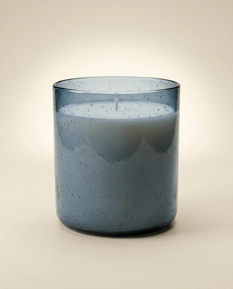 Blue candle in a glass container on a beige background