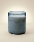 Blue candle in a glass container on a beige background