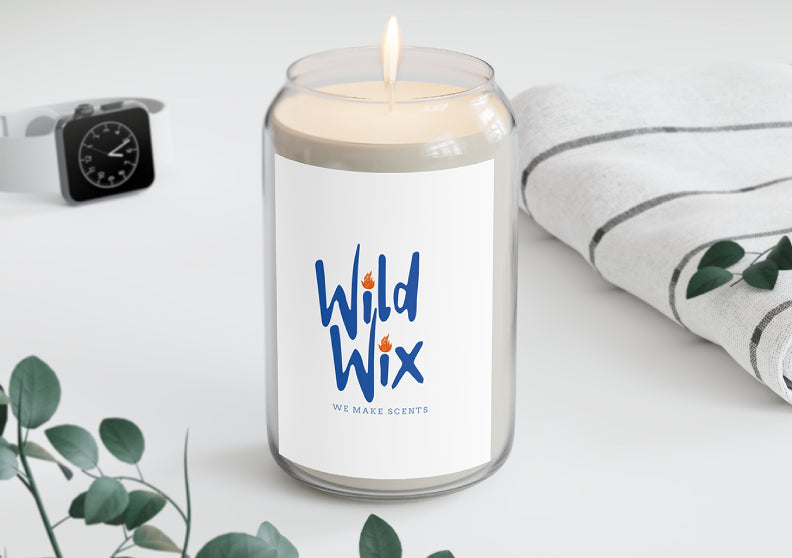 Candle with 'Wild Wix' branding on a white surface with greenery